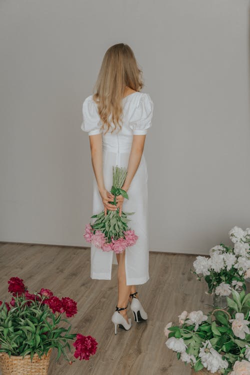 Woman in White Dress Holding Bouquet of Flowers