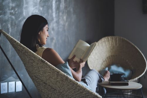 Free A woman enjoys a leisure moment reading a book in a cozy indoor setting. Stock Photo