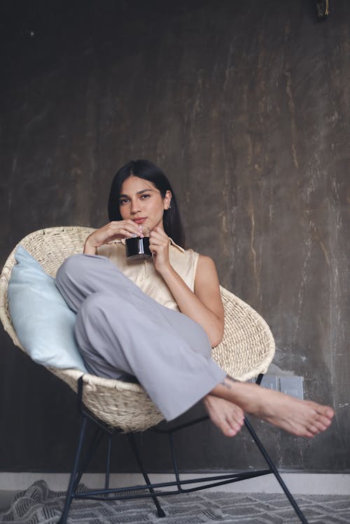 Free A Woman in Beige Top Sitting on a Wicker Chair Stock Photo