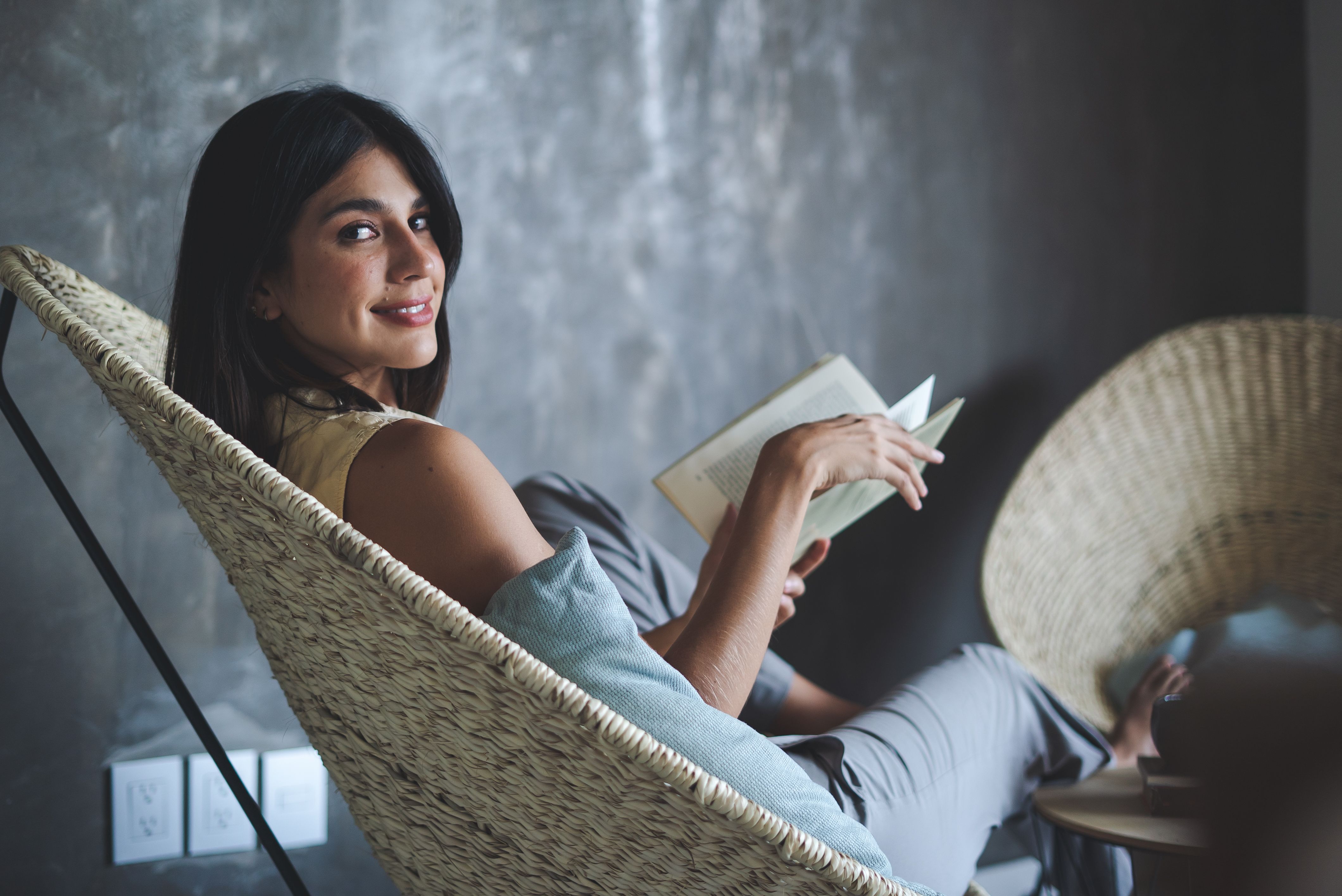 person reading a physical book in a cozy chair, natural light, calm atmosphere
