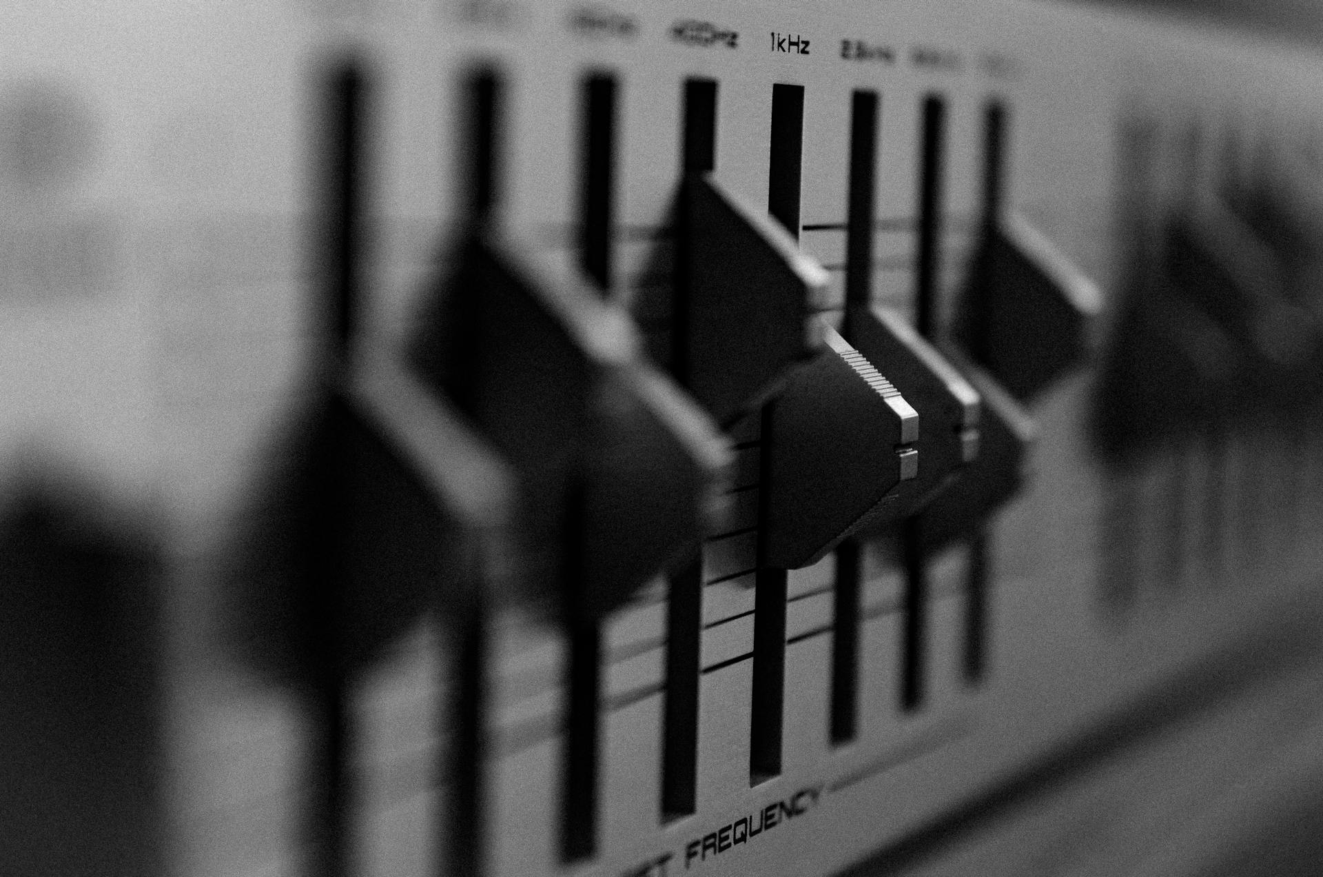 Black and white close-up of an audio mixer showing adjustment knobs and frequency settings.