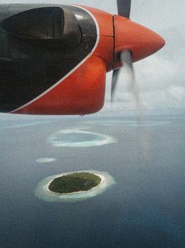 Photo by Sasha Maslova Scenic aerial view of a tropical island from an airplane window, showcasing clear blue waters and lush greenery.