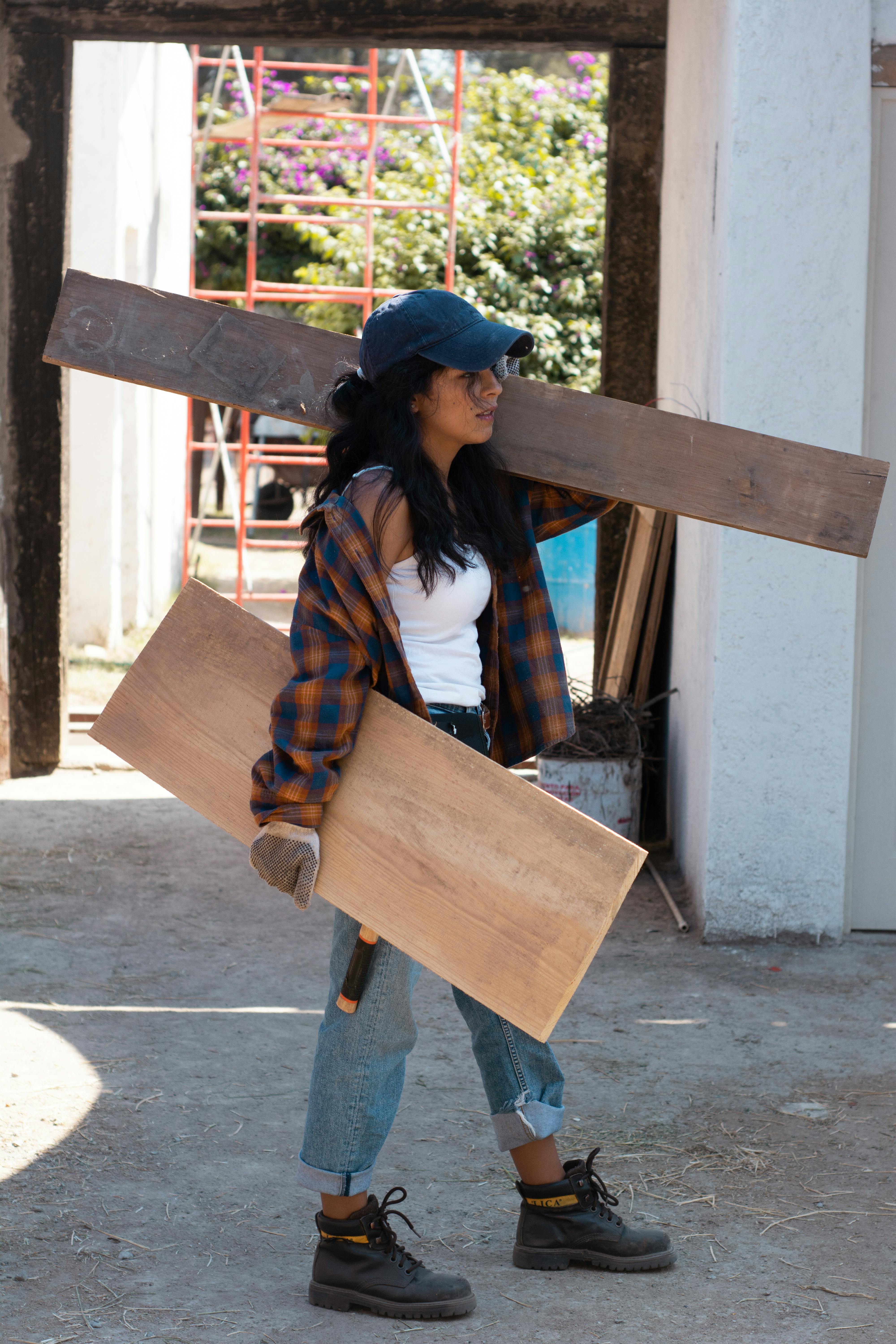 woman in red and white plaid shirt and blue denim jeans holding brown wooden board