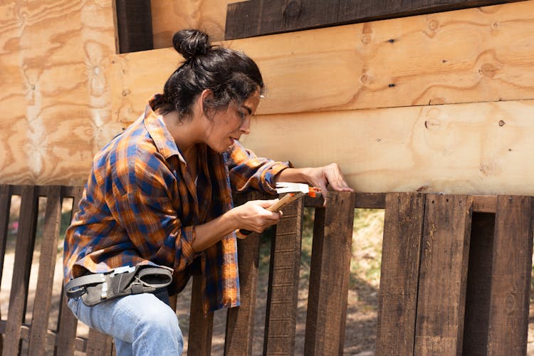 Woman In Plaid Long Sleeves Using A Hammer To Nail 