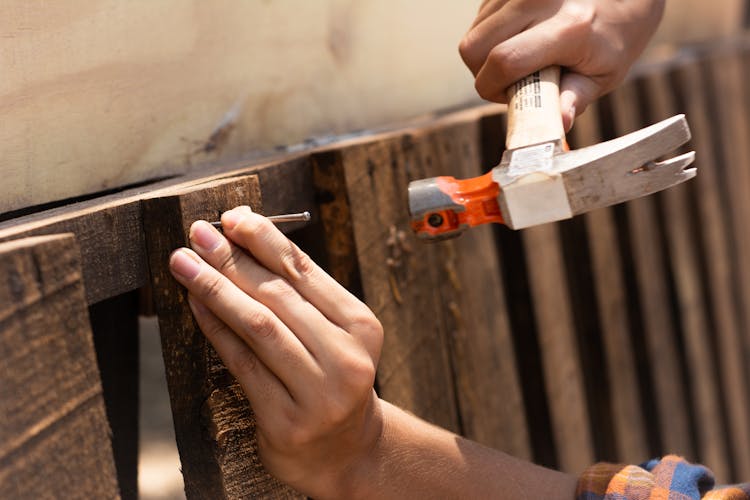 A Person Hammering A Nail 