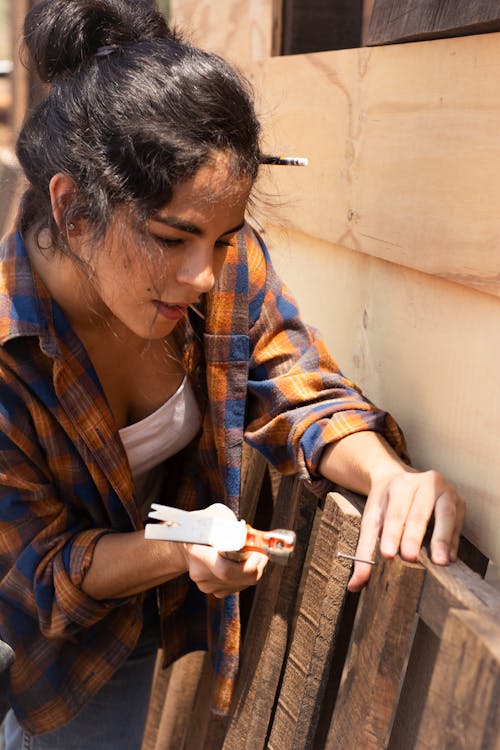 Woman hammering a Nail to a Wood Plank 