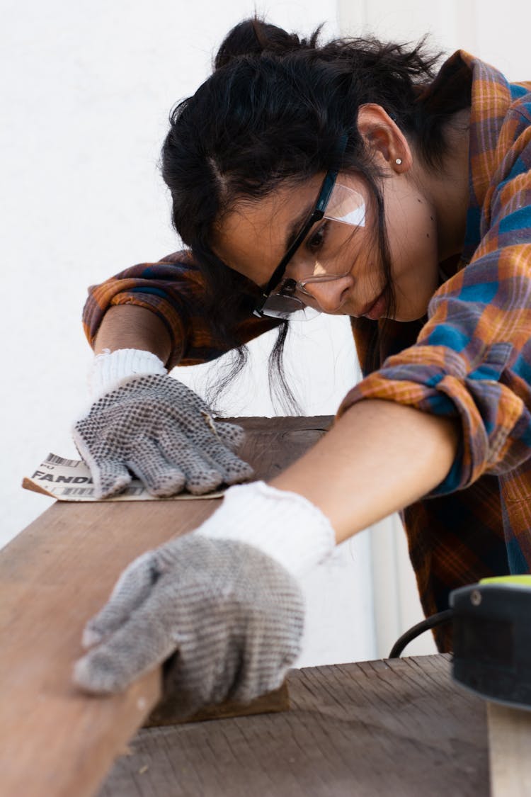 Woman In Protective Goggles Sanding The Wood 