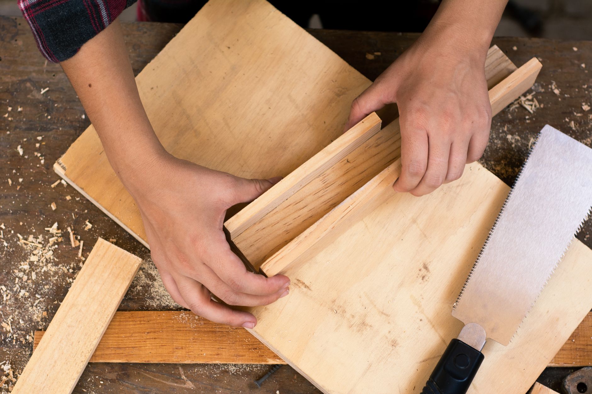 Close-up of hands crafting wood with tools in a carpentry workshop.