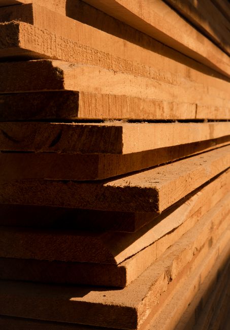 Close-up view of stacked wooden planks showcasing texture and sunlight shadows.