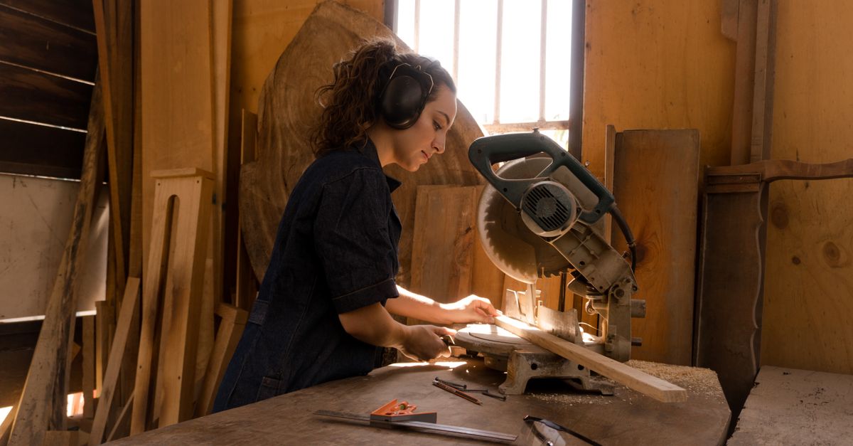 Dedicated female carpenter using a circular saw in woodworking studio, focused on craftsmanship and precision.