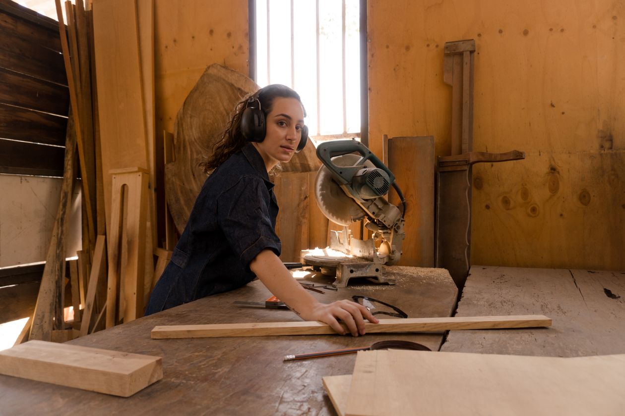 Elena Marsh, carpenter, measuring a board at the workbench