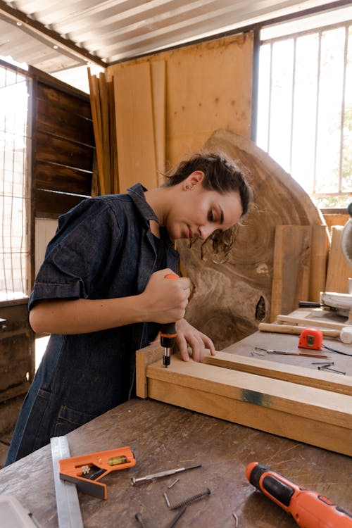 Free Woman in Blue Coveralls Using a Carpentry Tool  Stock Photo