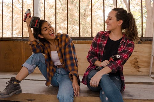 Free Two Women Wearing Plaid Shirts and Denim Jeans Holding Power Tools Stock Photo