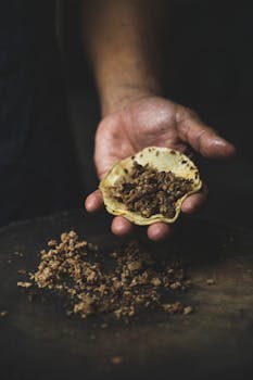 Close-up of a hand-held corn tortilla filled with seasoned meat, symbolizing authentic Mexican street food.