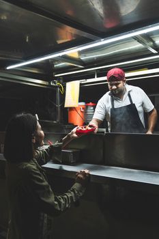 A street food vendor hands a taco to a customer at night, showcasing Mexican street cuisine.