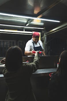 A street vendor serves authentic Mexican tacos to customers at a taco stand at night.