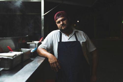 Free Portrait of a street vendor at night in Mexico, wearing an apron and cap, ready to serve food. Stock Photo