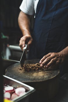 Chef chopping meat for traditional Mexican tacos on a wooden board, perfect for food photography enthusiasts.