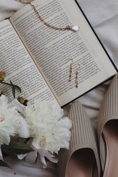 An elegant arrangement featuring a book, jewelry, and white flowers for a serene lifestyle aesthetic.