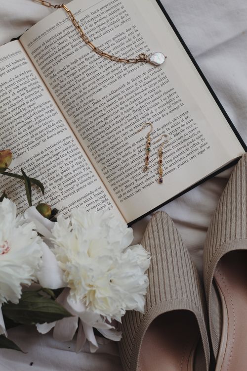 Free An elegant arrangement featuring a book, jewelry, and white flowers for a serene lifestyle aesthetic. Stock Photo