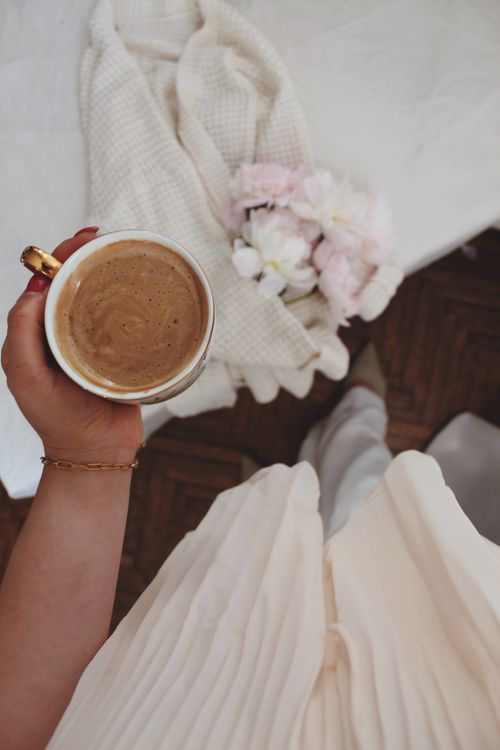 Free A cozy morning scene with a coffee cup, soft blanket, and flowers, captured from above. Stock Photo