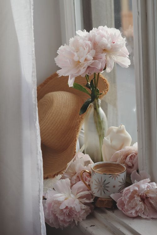 Free Charming setup with peonies, a cup of coffee, and a sun hat by the window. Stock Photo
