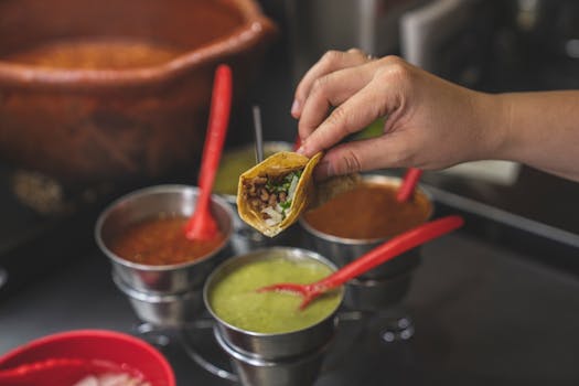 Close-up of a hand holding a taco with various sauces, capturing the essence of Mexican street food.
