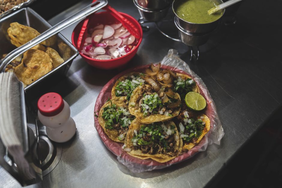 Delicious Mexican tacos with fresh toppings and sauces on a street food stall.