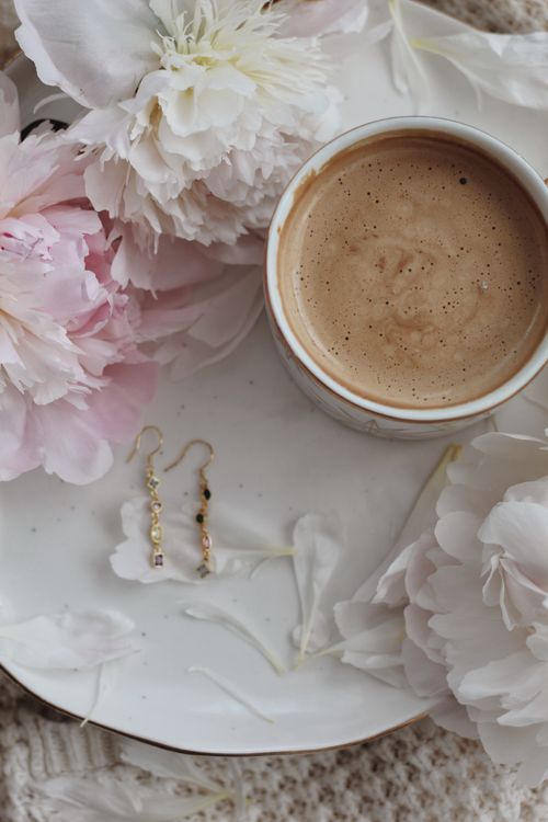 Free A cup of coffee on a plate with flowers and earrings, shot from above for a serene still life. Stock Photo