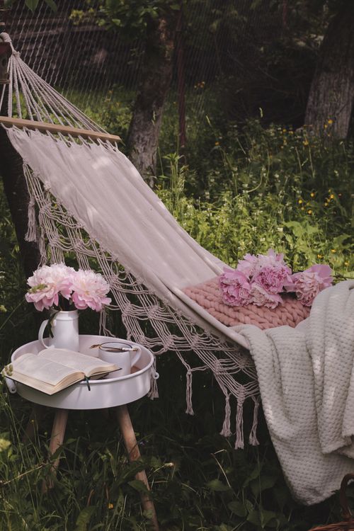 Free A cozy hammock with pink peonies, book, and tea on a sunny day. Stock Photo