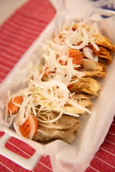 Delicious assortment of Mexican tacos topped with fresh vegetables and cheese, presented on a tray.