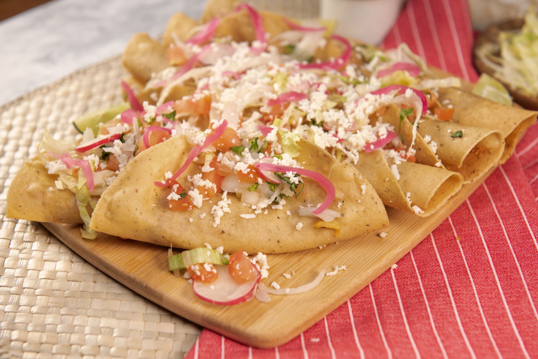 Platter of flautas topped with crema and crumbled cheese