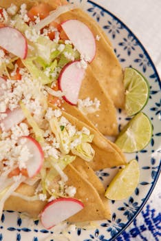 Close-up of delicious Mexican tacos topped with fresh radishes, lettuce, and cheese.