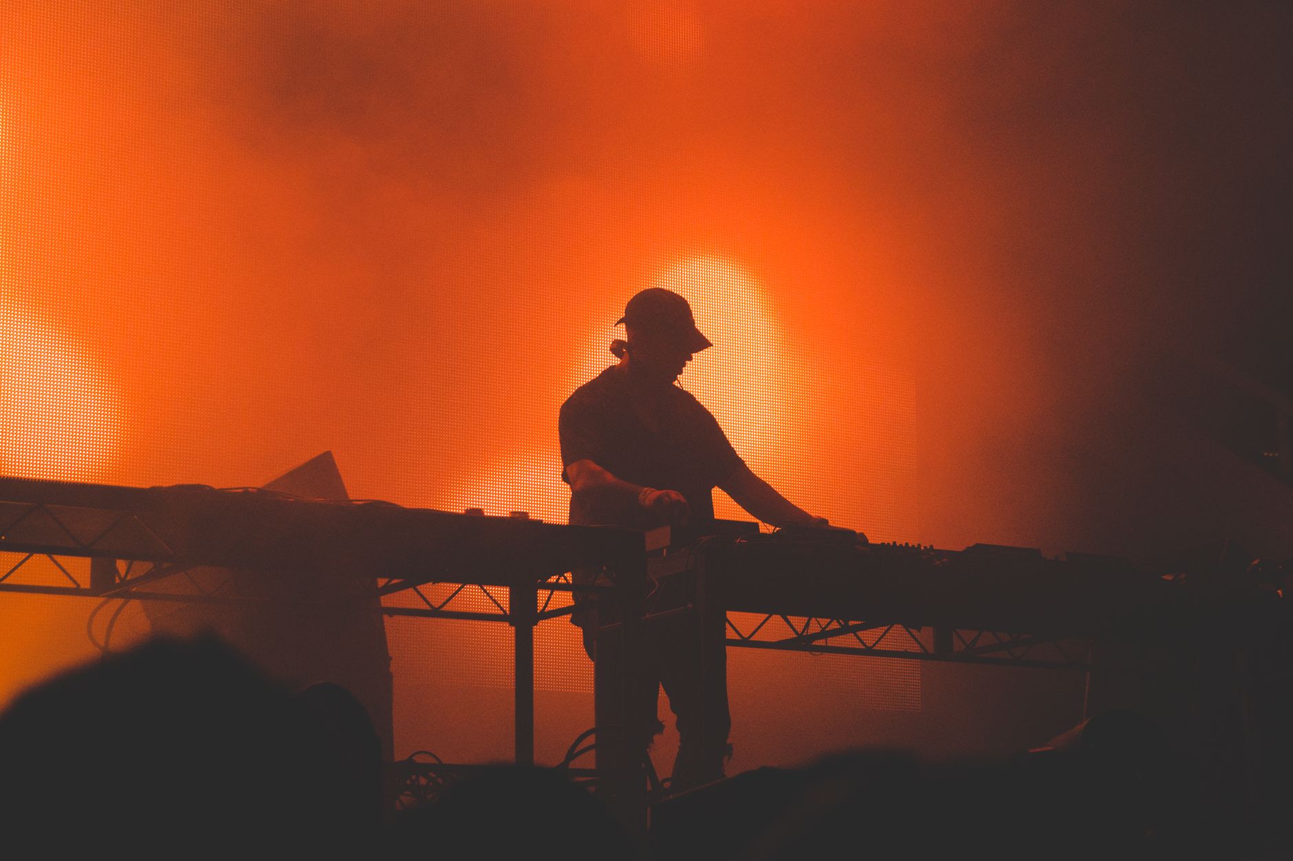 Een DJ-silhouet creëert een energieke sfeer met levendige rode verlichting tijdens een nachtclub evenement.