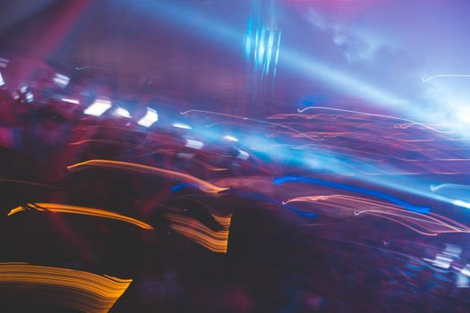 Energetic nightclub atmosphere with vibrant colored lights and abstract motion blur.