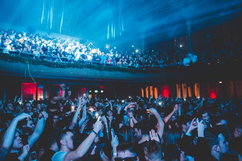 Free A large, energetic crowd enjoys a live music performance in a nightclub with vibrant lighting. Stock Photo