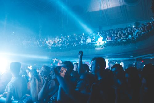 Free Energetic crowd enjoying live concert in a bustling nightclub, filled with vibrant blue lights and exciting atmosphere. Stock Photo
