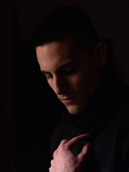 Free A contemplative young man gazes downwards in a shadowy studio portrait. Stock Photo