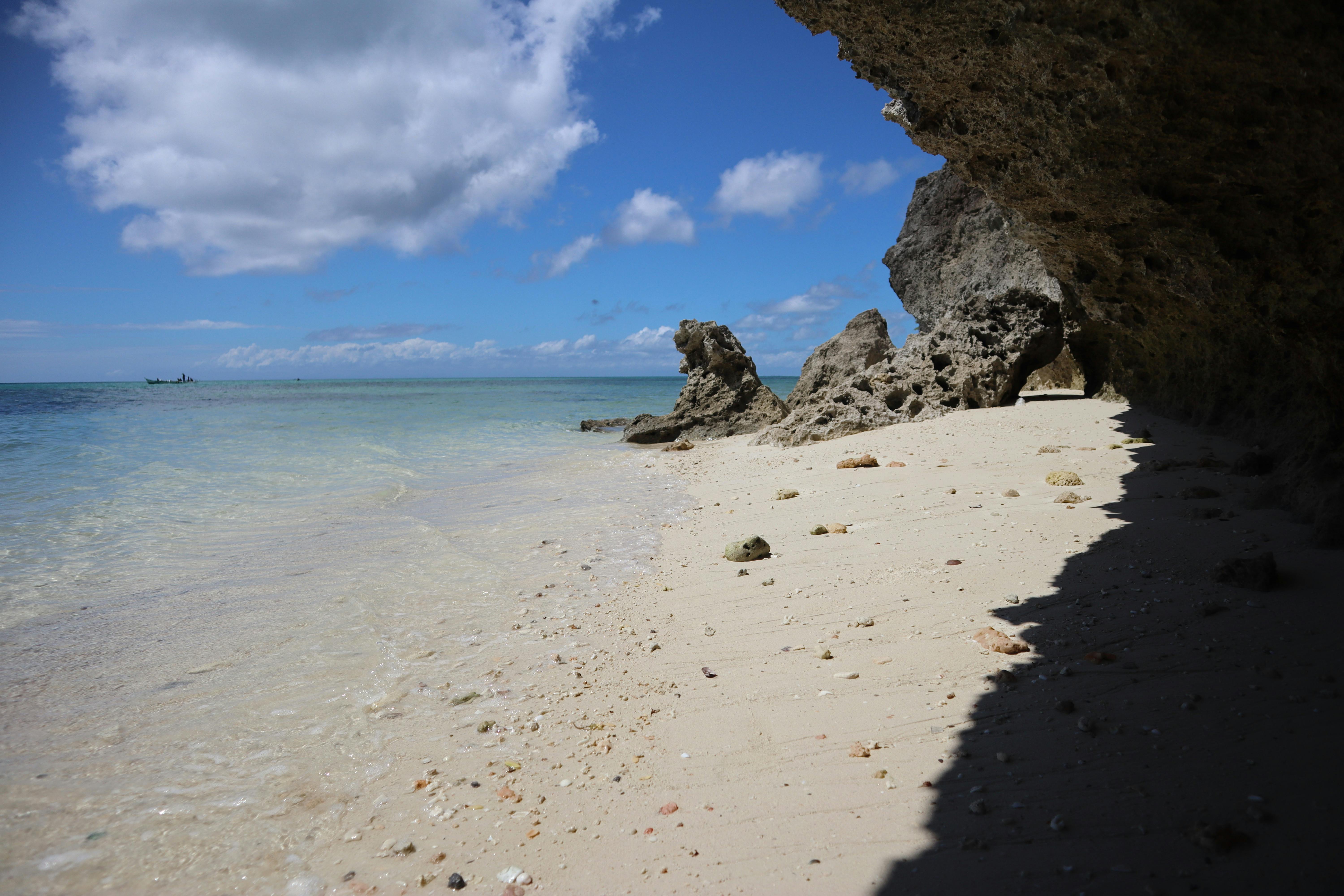 A picturesque beach with rocky cliffs and clear blue sky. Ideal for nature lovers.