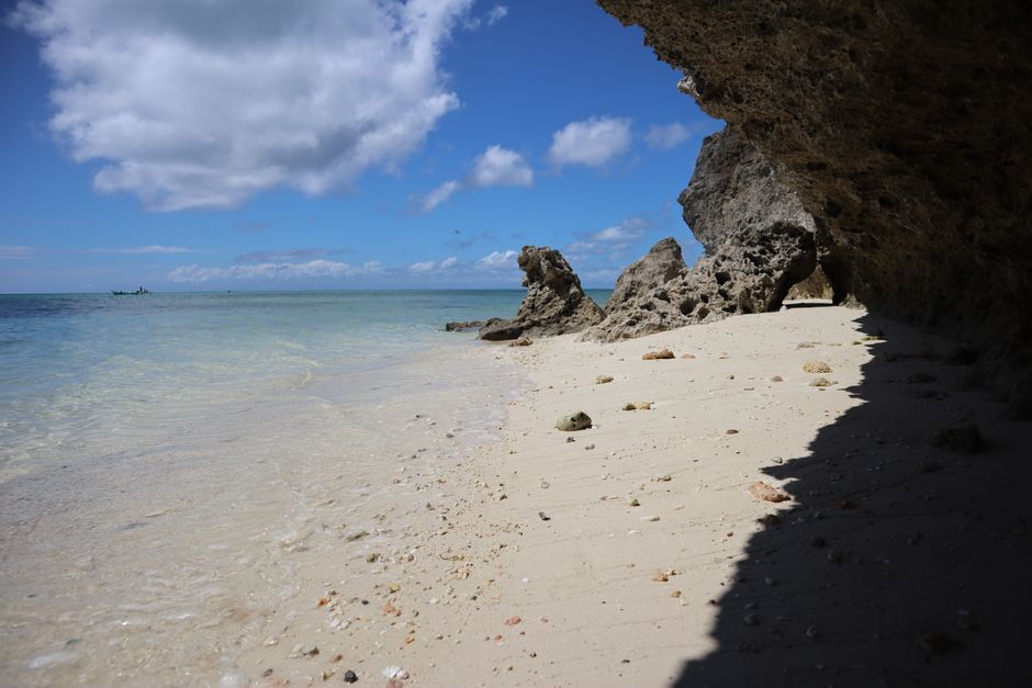 A picturesque beach with rocky cliffs and clear blue sky. Ideal for nature lovers.