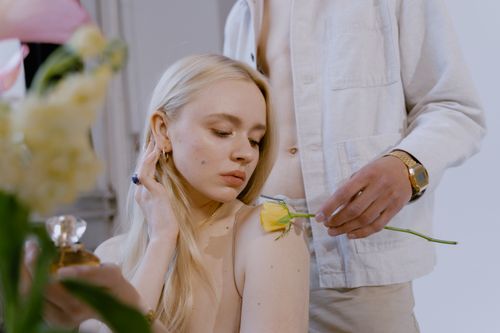 Free A serene portrait of a woman with a yellow rose on her shoulder, highlighting elegance. Stock Photo