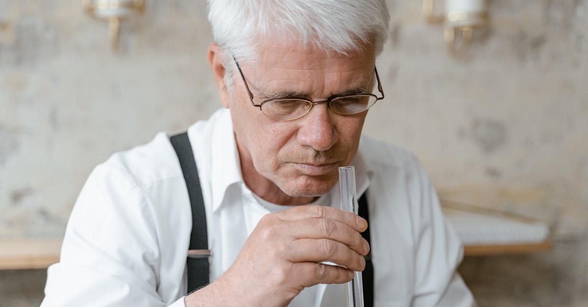 Elderly man analyzing scent from a test tube, focused on fragrance. Elderly man analyzing scent from a test tube, focused on fragrance.