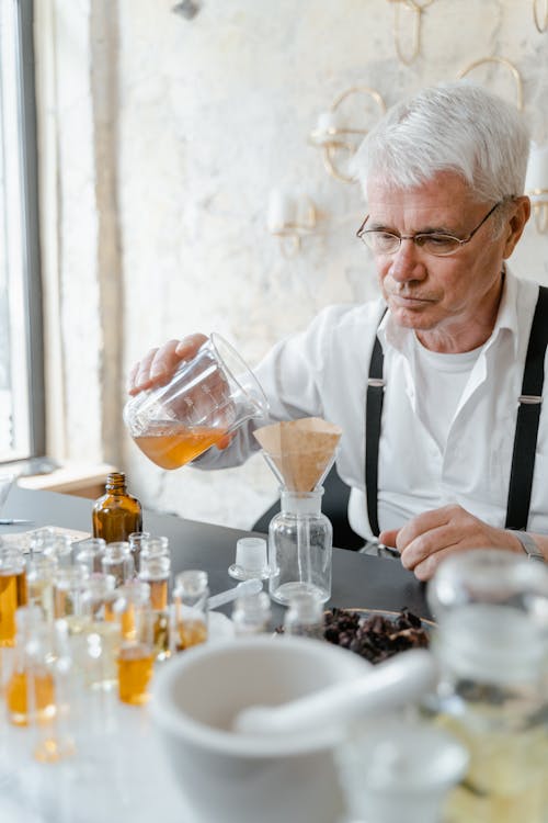 Free A Man Pouring Yellow Liquid in the Glass Jar Stock Photo