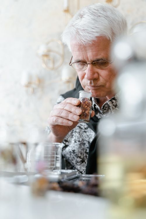 Free Elderly man enjoying aromatic scent indoors, showcasing fragrance and aroma exploration. Stock Photo