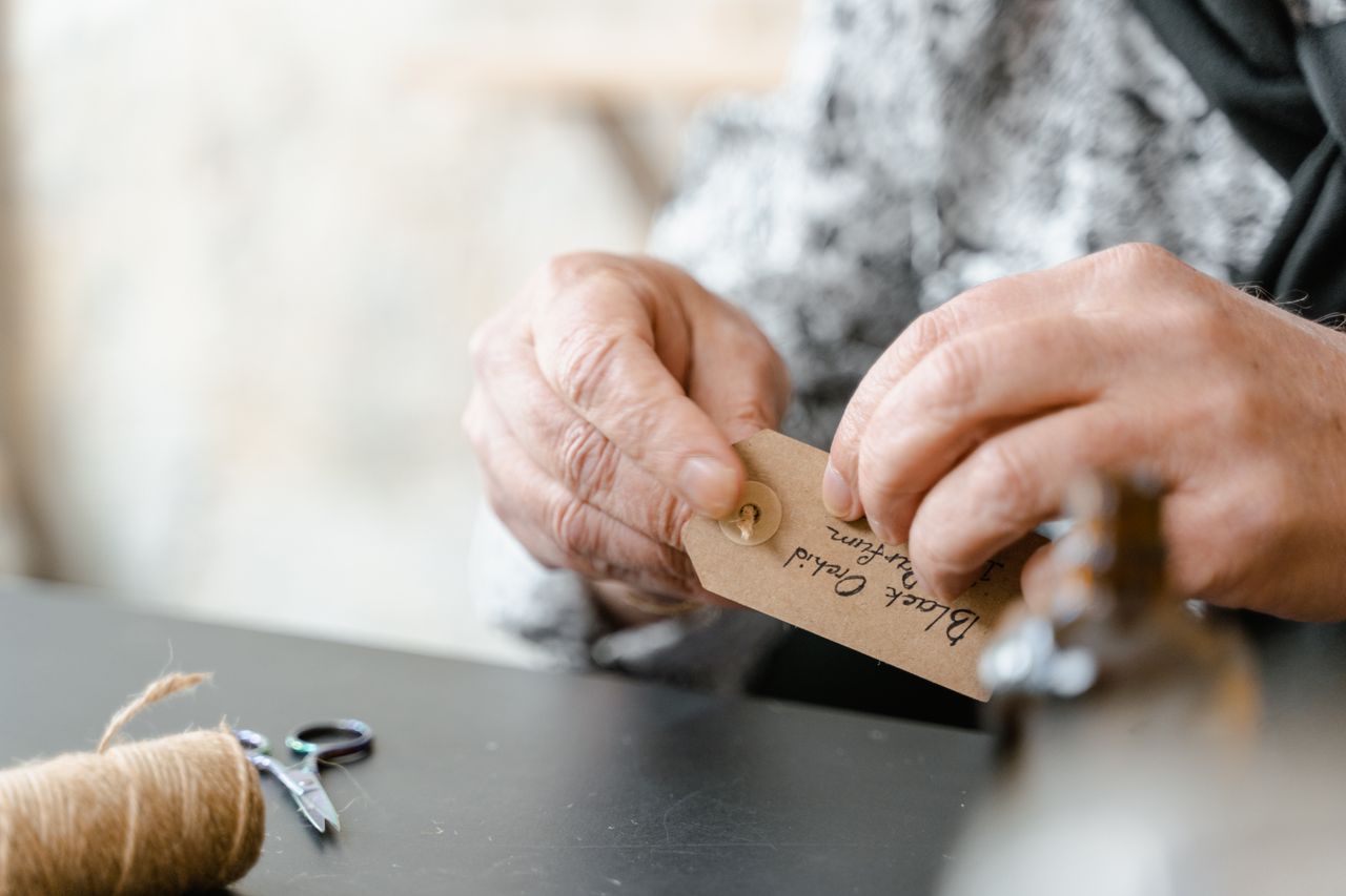 Detailed view of hands attaching a handmade gift tag with jute string, emphasizing craftsmanship.