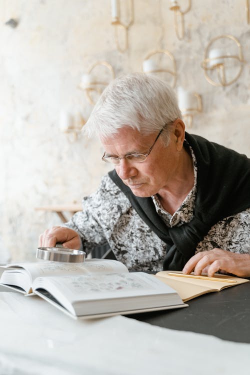 Elderly Man in Floral Shirt Holding Magnifying Glass