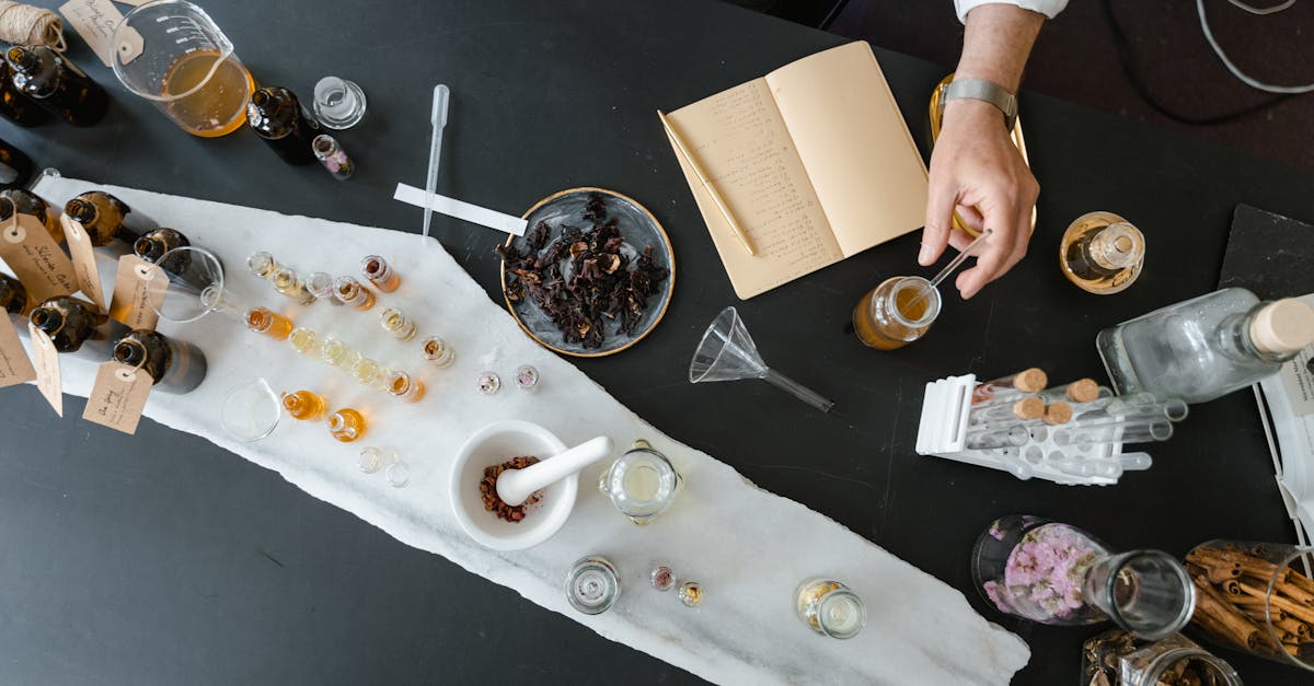 A clear bottle filled with fresh lavender essential oil surrounded by blooming lavender flowers and green leaves on a wooden surface.