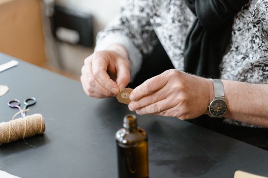 Close-up of hands crafting with brown paper, string, and scissors on a table.