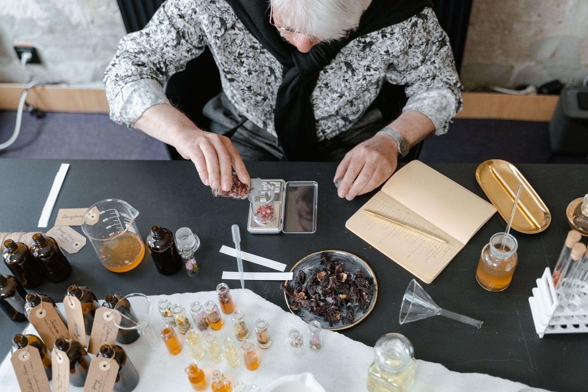 Top view of a professional aromatherapist preparing essential oils in a modern workspace.