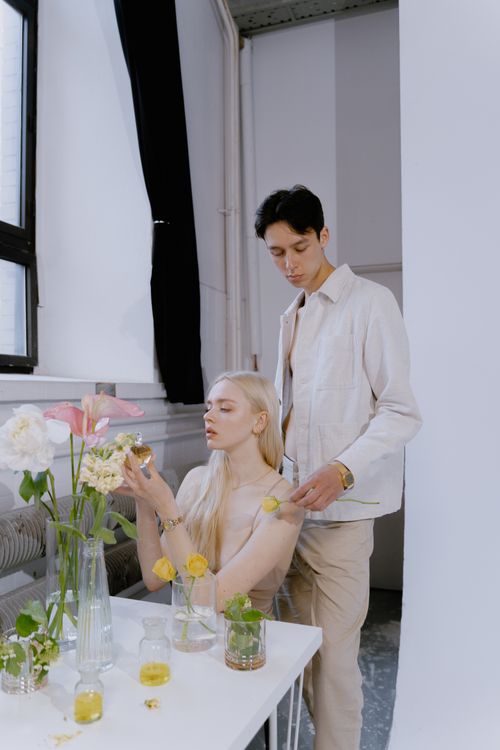 Free A fashionable duo showcases fragrance amidst elegant, floral decor in a chic studio. Stock Photo